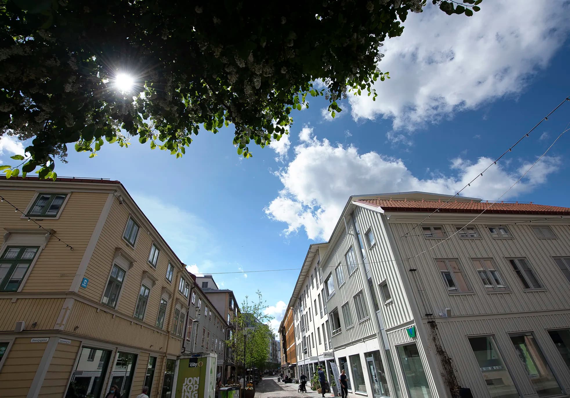 Gågata i stadskärna med ljusa trähus, butiker i bottenplan en solig dag
