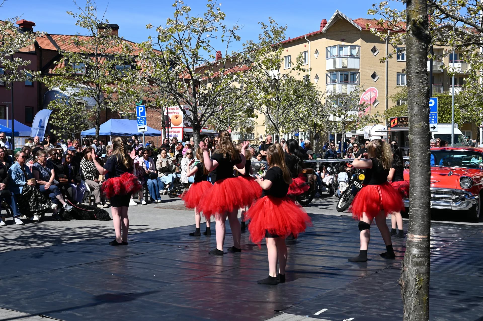 Dansgrupp uppträder utomhus på Citydagen inför publik, klädda i svarta tröjor och röda tyllkjolar