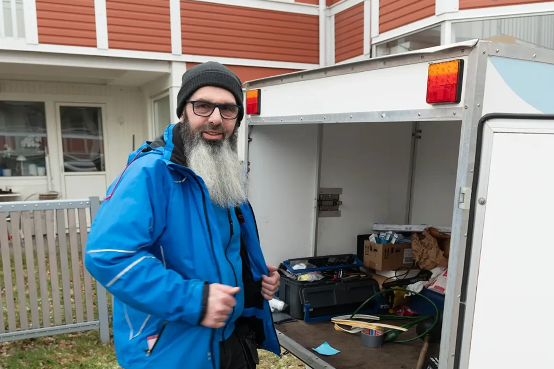 Fastighetsvärd vid servicebil utanför lägenhetshus, redo för service och felanmälningar